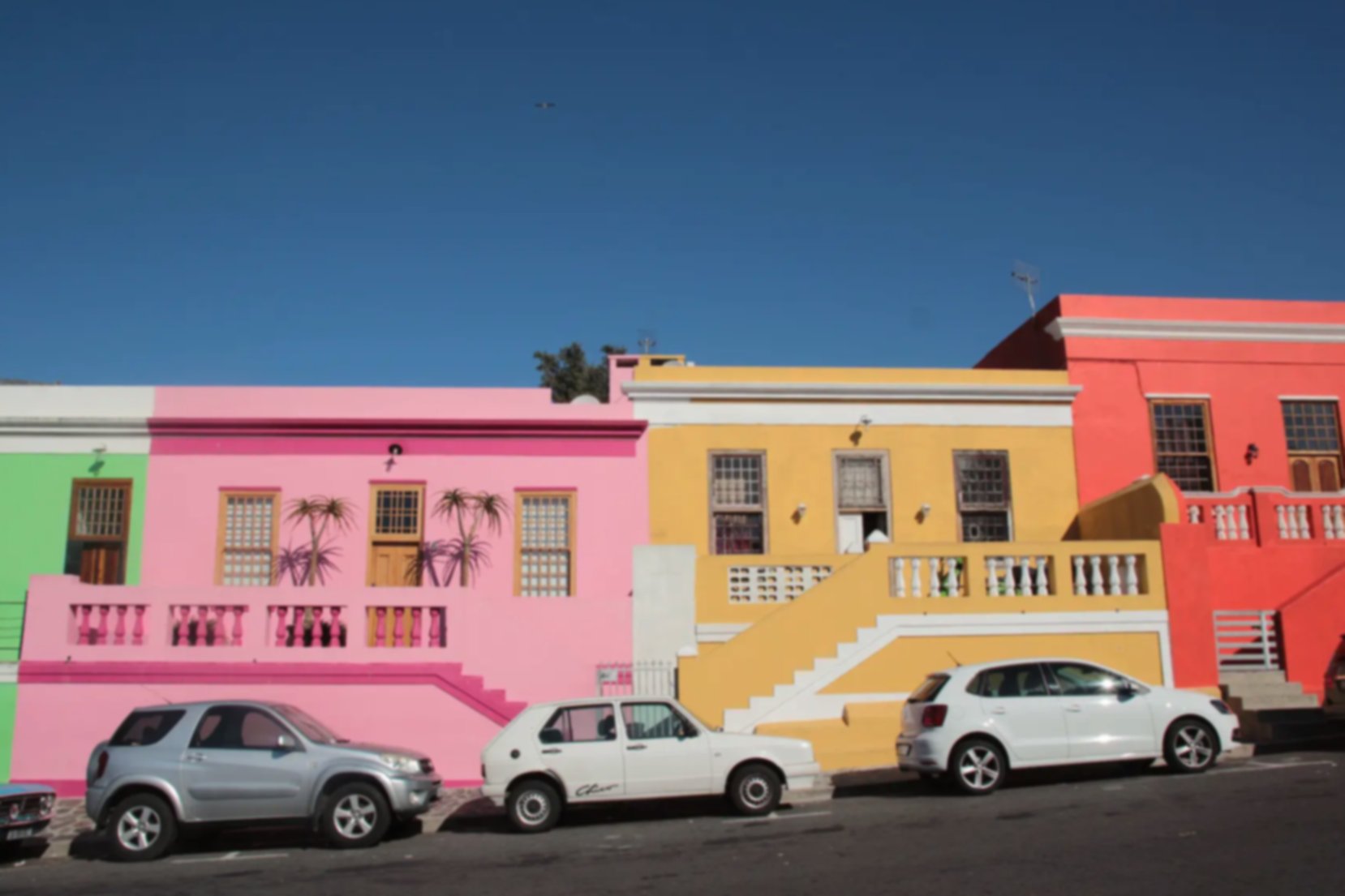 An inclined street is lined with colorful houses of similar shape and size, in Bo-Kaap, Cape Town