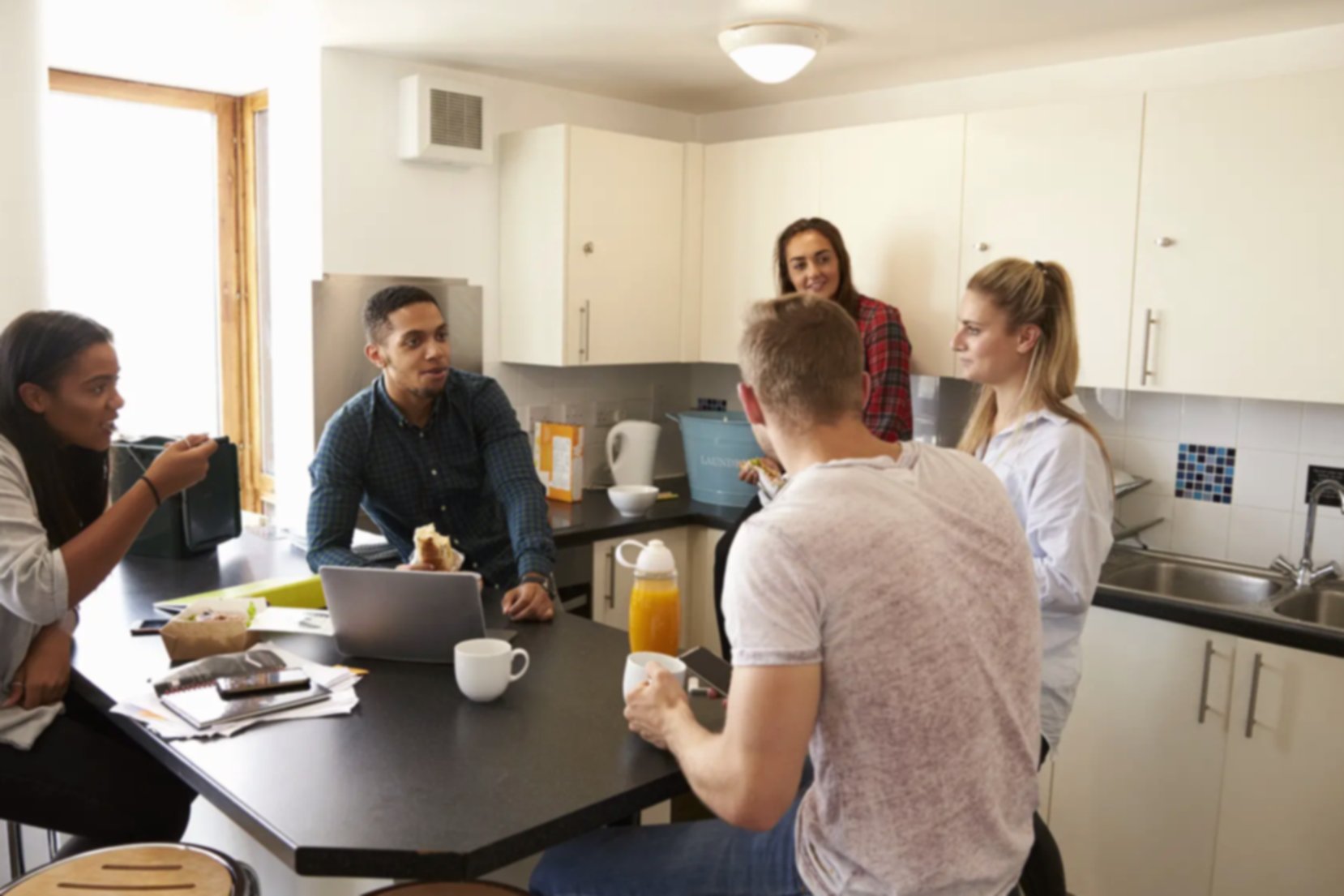 A group of 20-somethings socialize in a shared kitchen