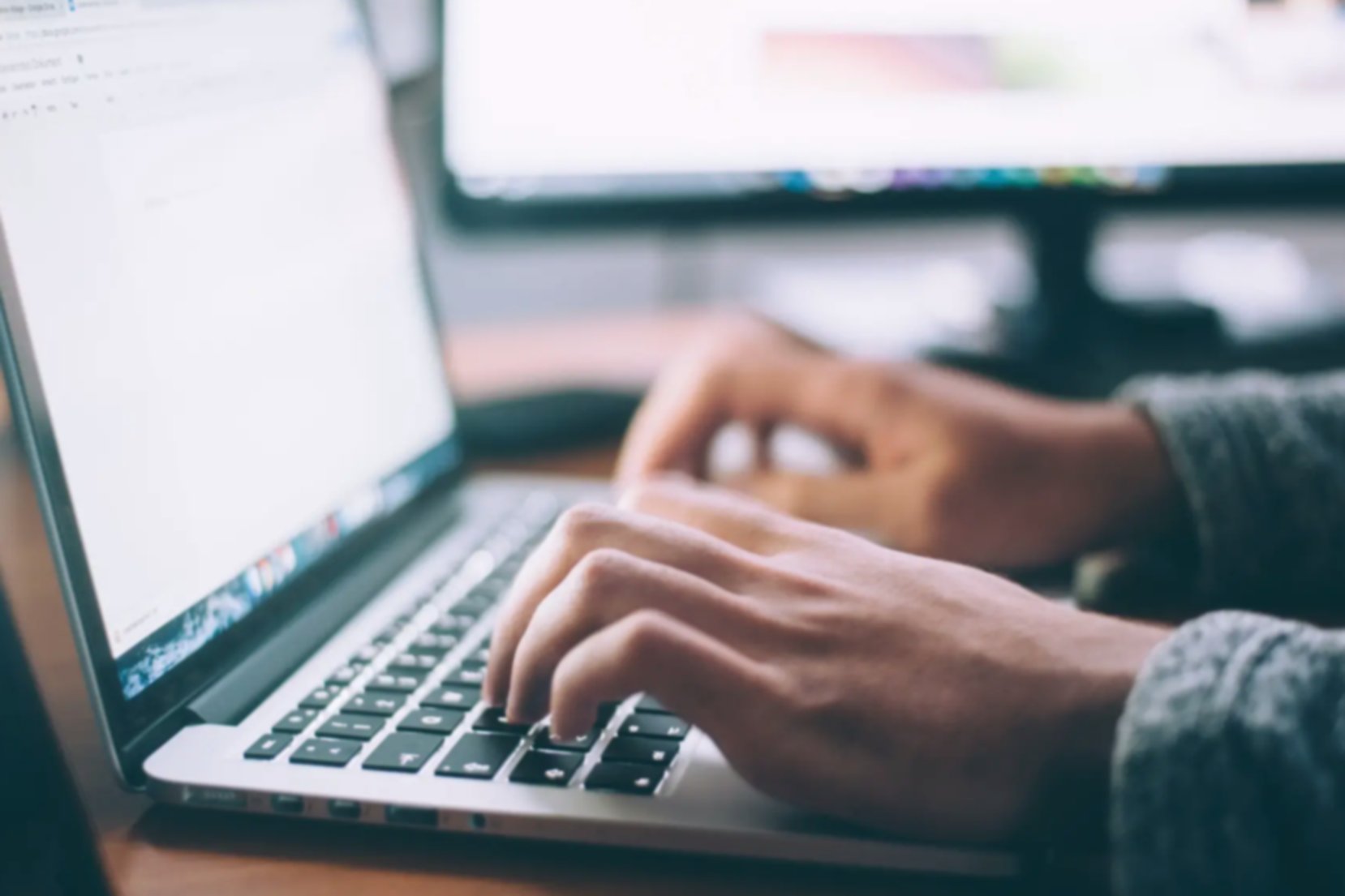 A close-up of some hands typing on the keyboard of a laptop