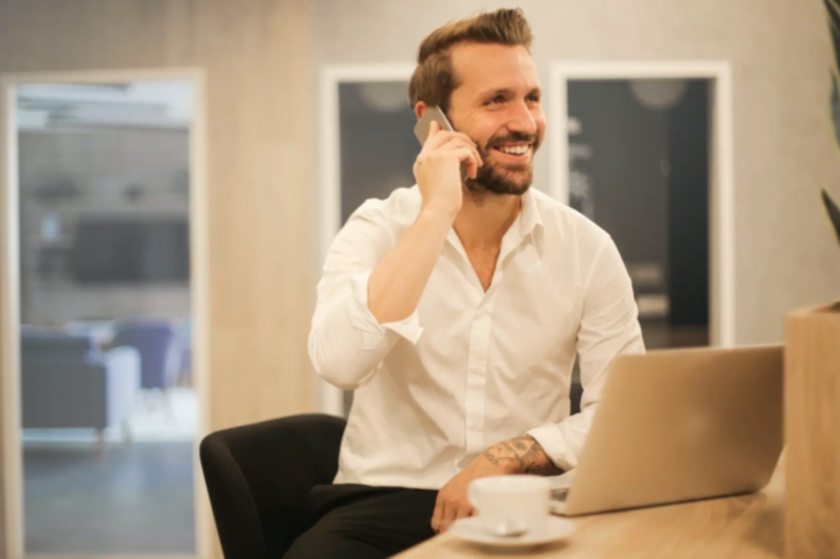 a man dressed professionally smiling while he chats on his mobile in an office