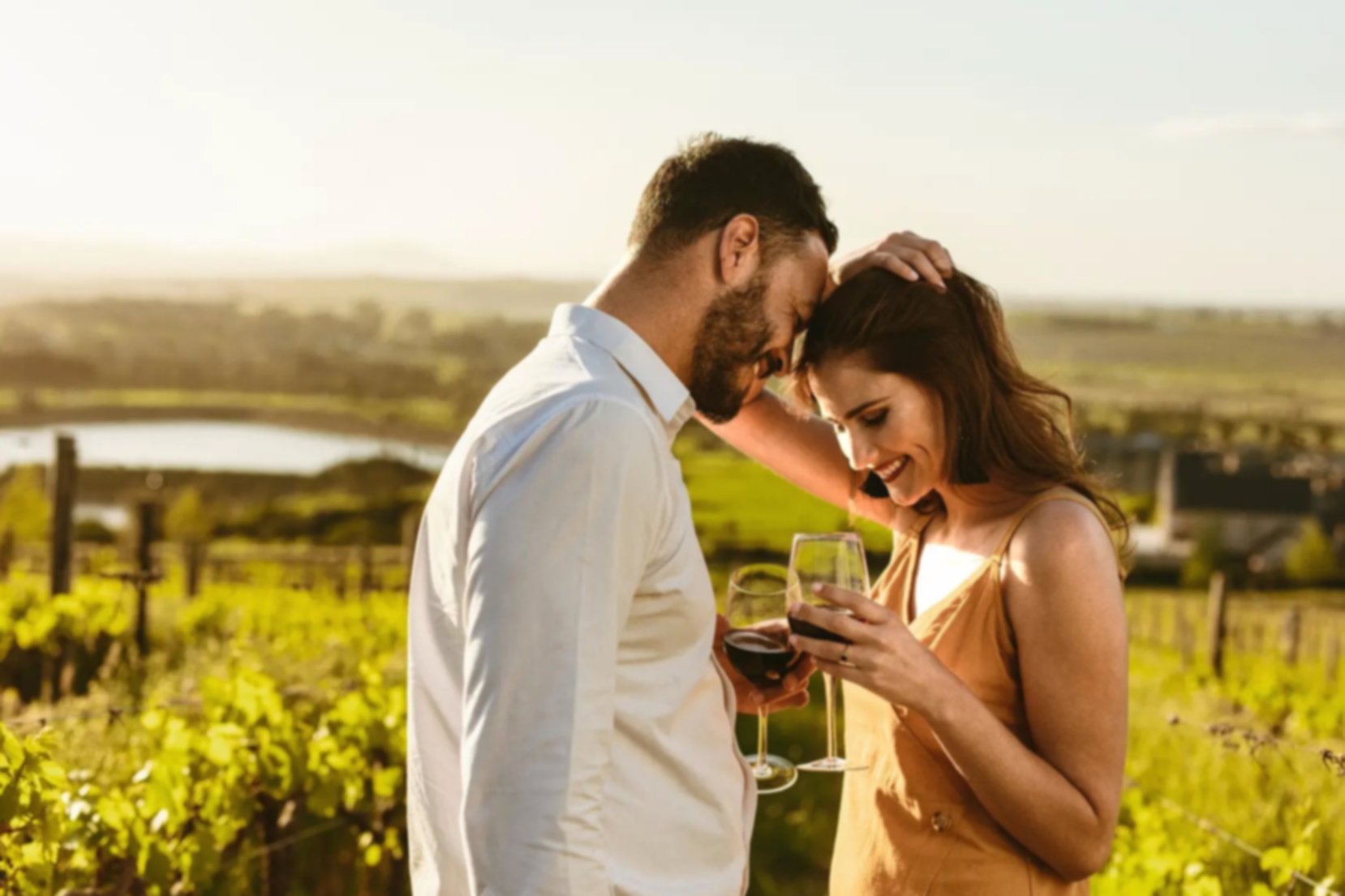 Couple on a romantic date standing together drinking red wine in a wine farm in South Africa.