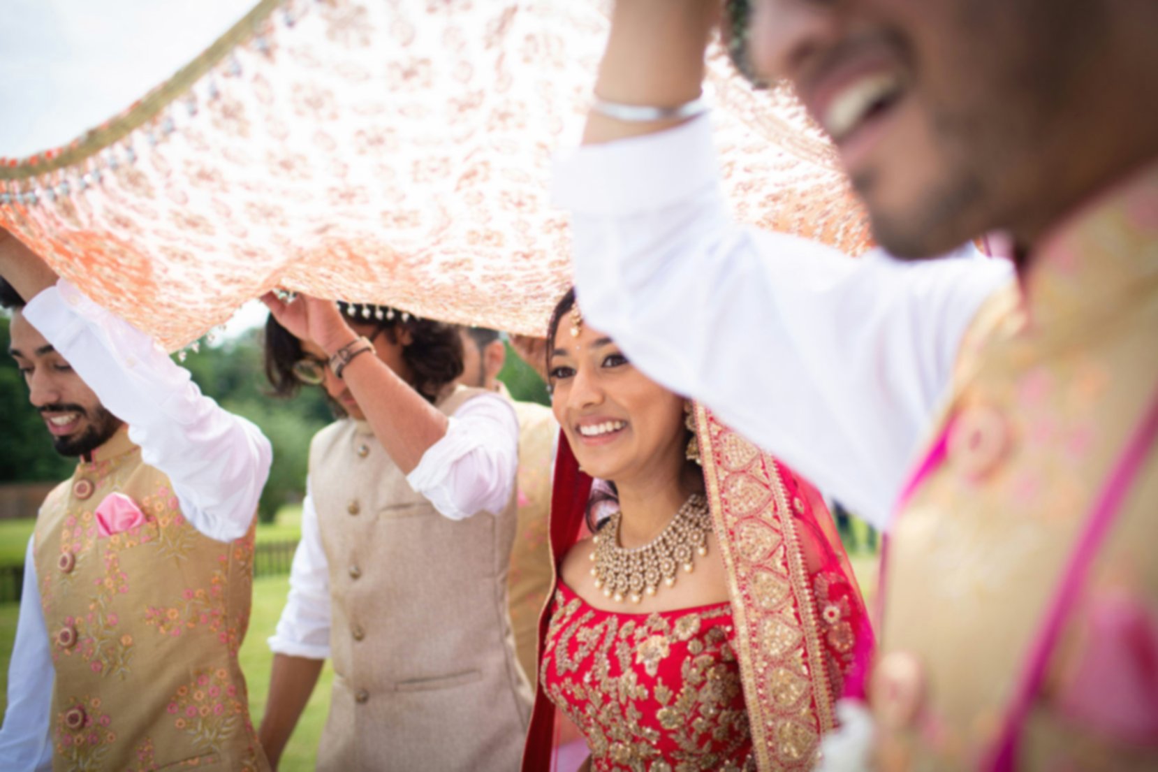 Beautiful bride walking toward the altar, covered by a veil that's been held by family members.