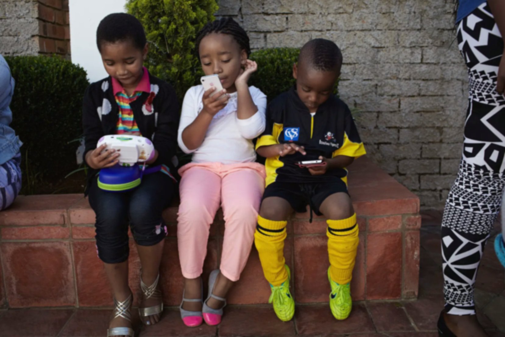 three little kids playing on mobile phones