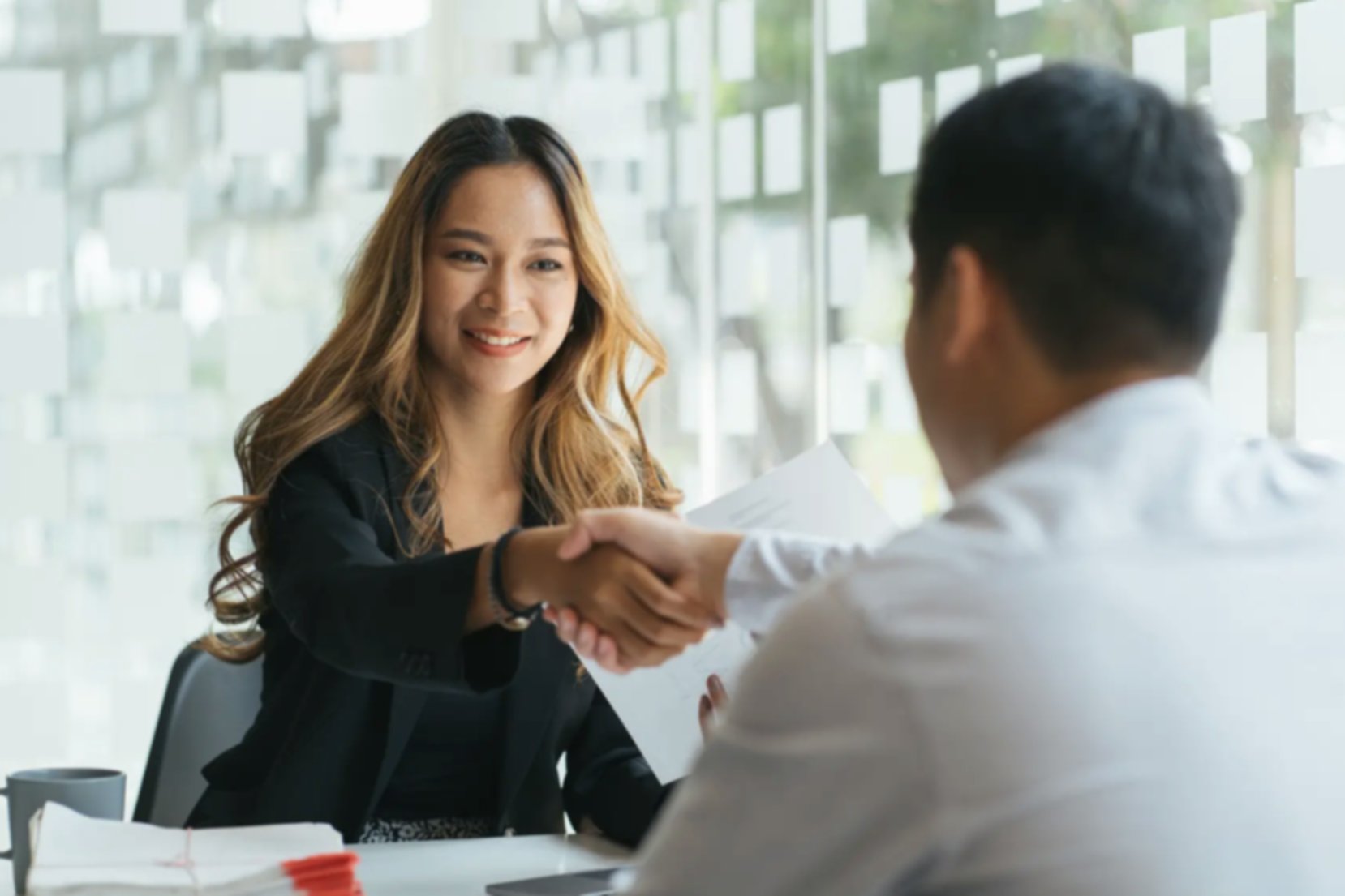 A woman shaking hands with a man in an office