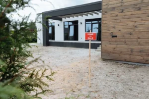 Casa de estilo moderno con jardín y letrero de venta