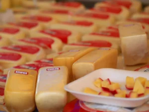 Puesto de queso tradicional con ruedas y mesas en un mercado