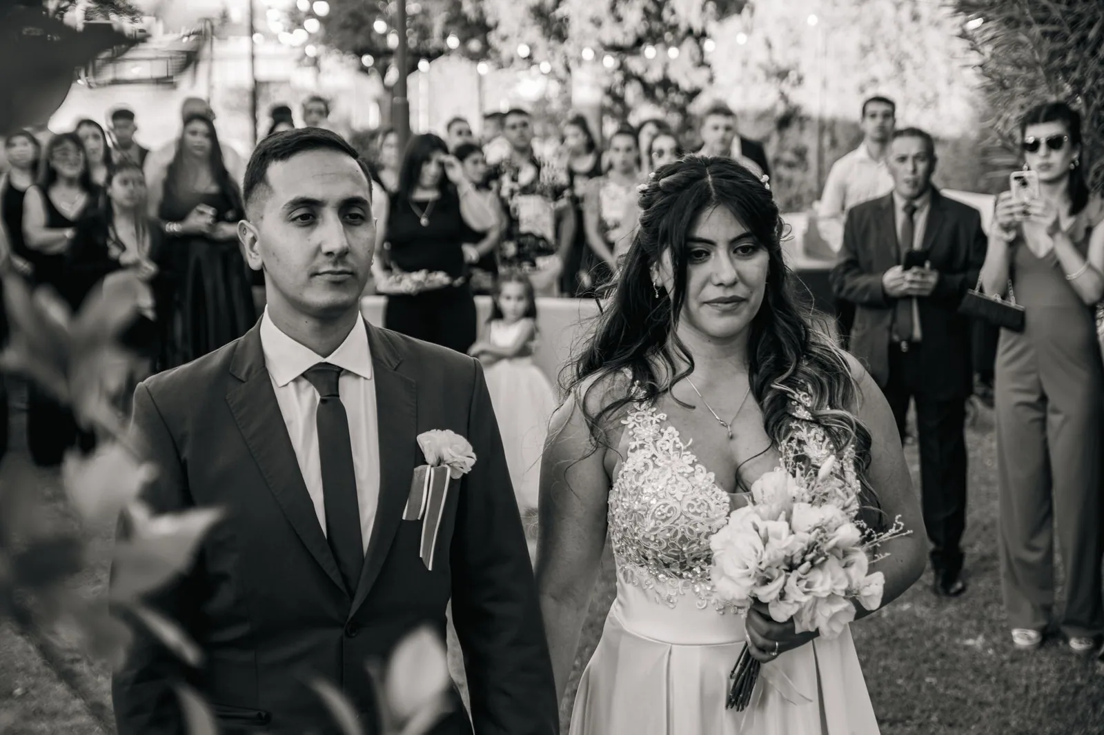 Pareja sonriendo bajo arcos florales en boda al aire libre