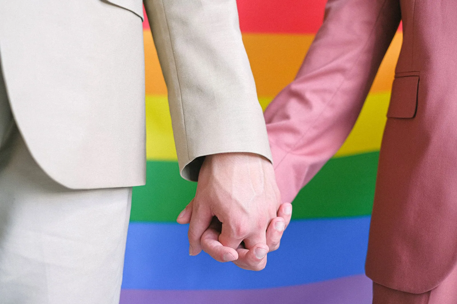 Pareja sosteniendo una bandera arcoíris en una plaza