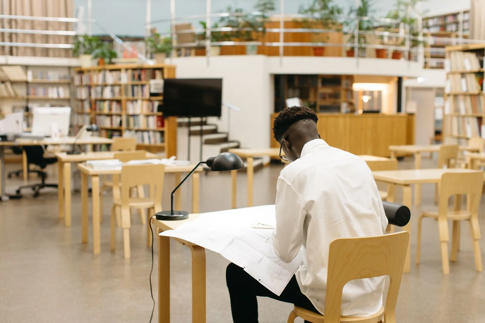 Estudiante revisando documentos en biblioteca universitaria