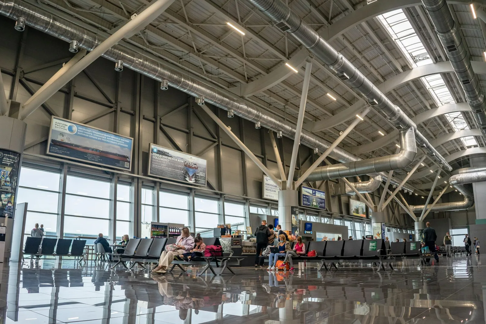 Terminal moderno de aeropuerto con pasajeros y pantallas de información