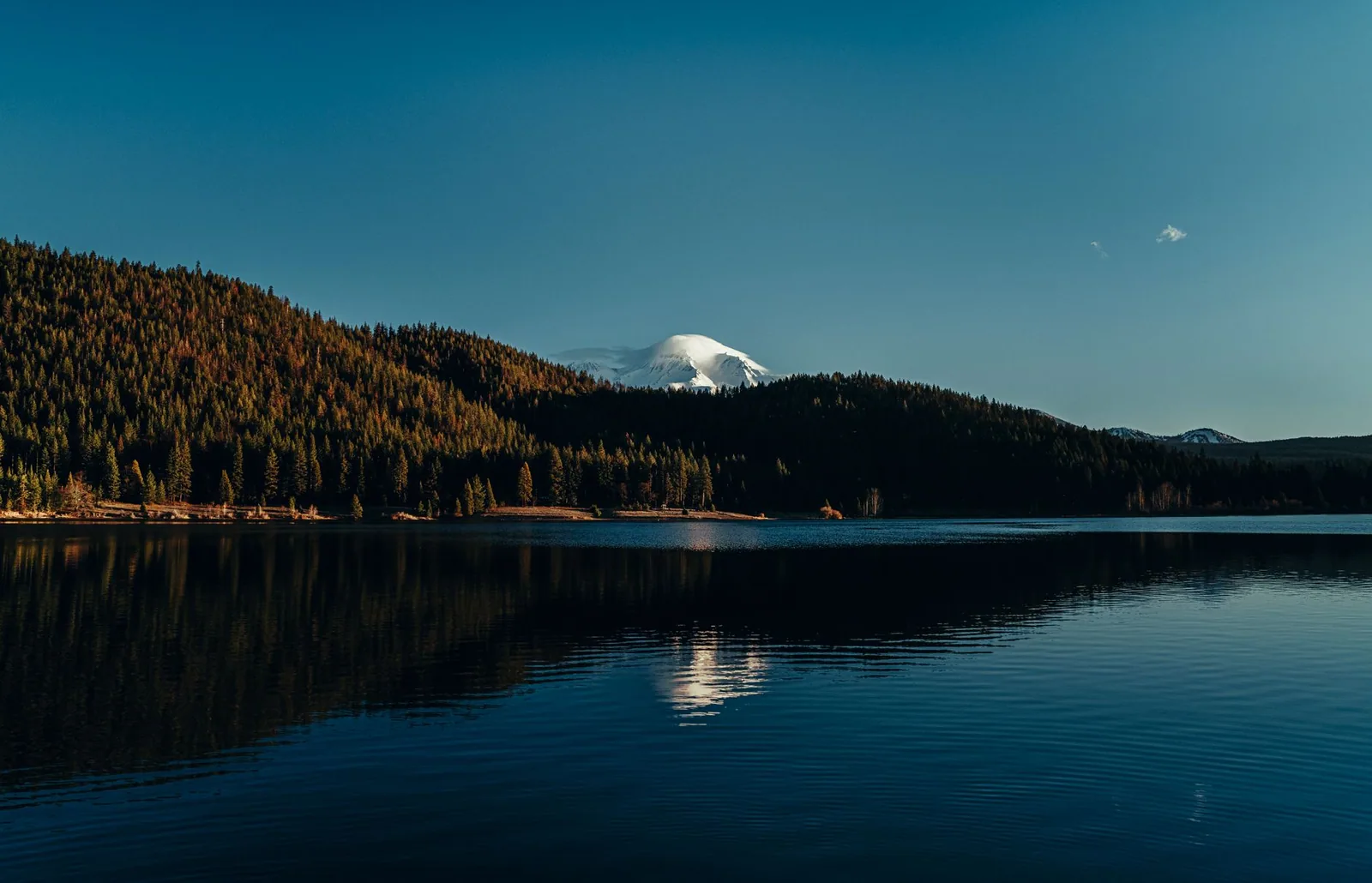 Lago de montaña con picos nevados y cielo azul en Suiza