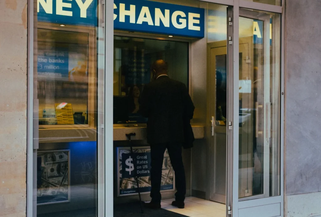 Mano sosteniendo billetes de varias divisas junto a un teléfono móvil
