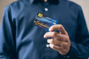 Mano sosteniendo tarjeta de crédito frente a terminal de pago