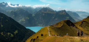 Sendero junto a un lago de montaña con picos nevados al fondo