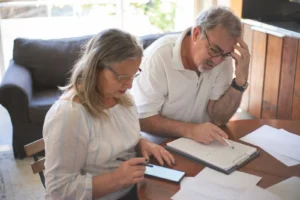 Pareja mayor revisando documentos de pensión en casa